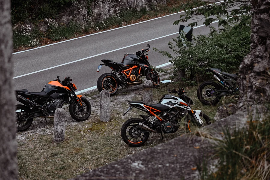 Un gruppo di moto arancioni e nere in sosta accanto a una strada di montagna.